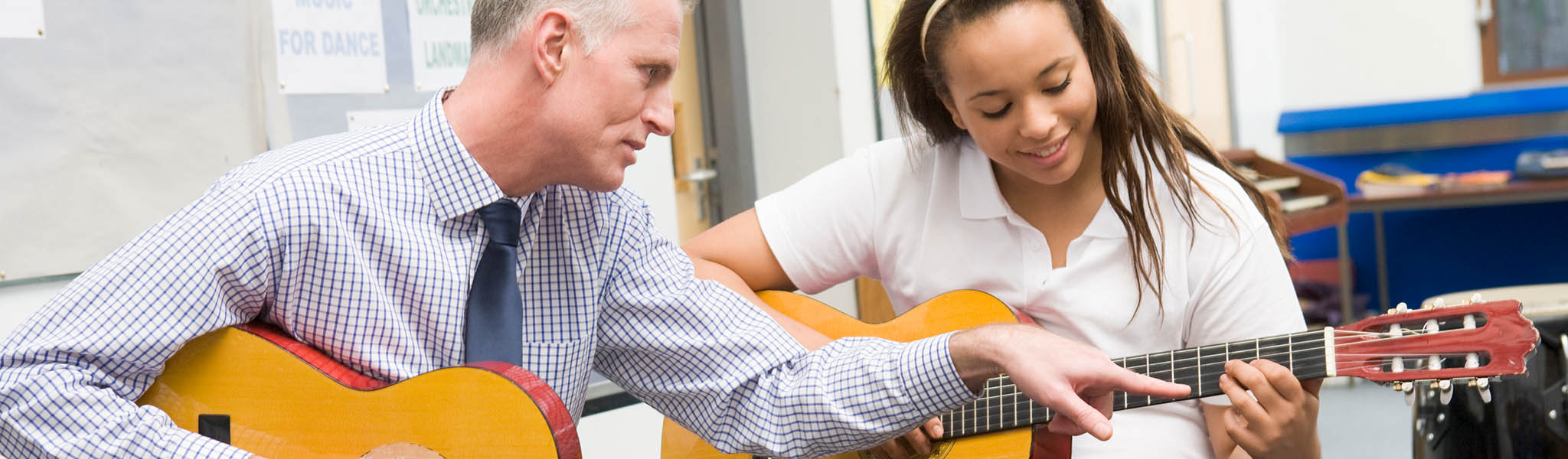 Headers-Large-2048x600_0000s_0002_iStock-120909026 Guitar instructor teaching guitar student